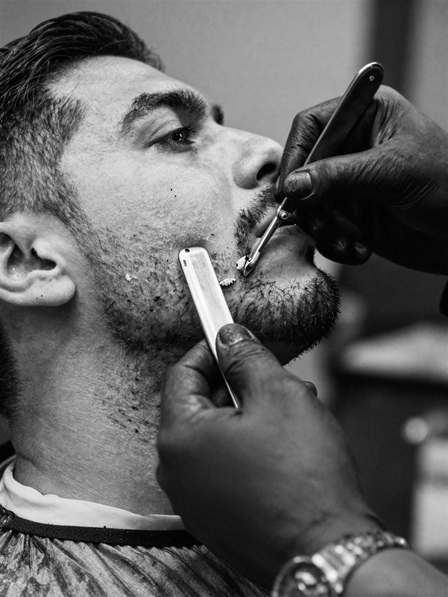 Barbero perfilando una barba con navaja